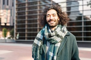 Smiling man in a green coat with grown-out full-length curly hair